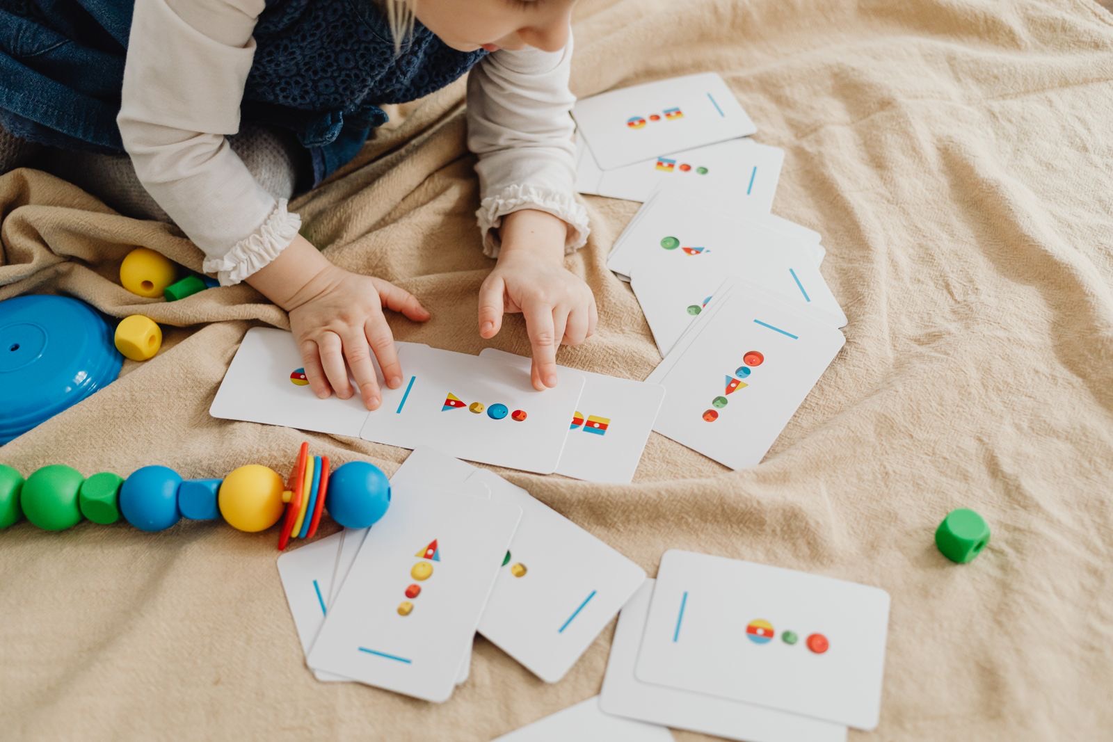 A child laying out printed cards on cream linen
