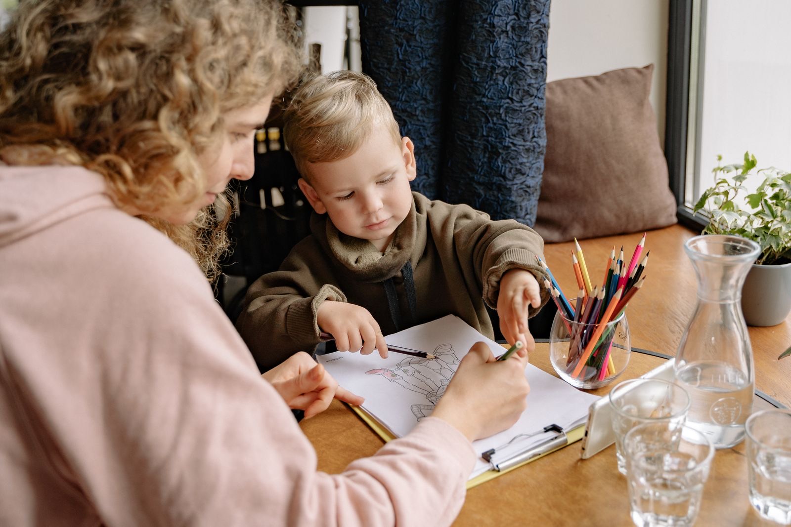 An adult and a young child colouring a printed sheet together at a table