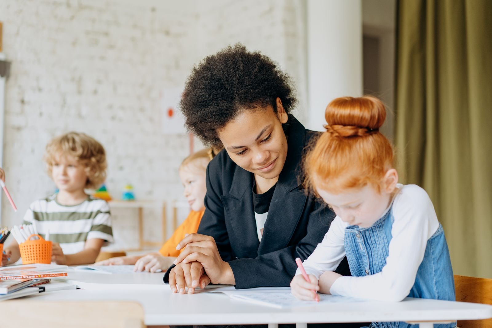 An adult sitting alongside a child writing at a table